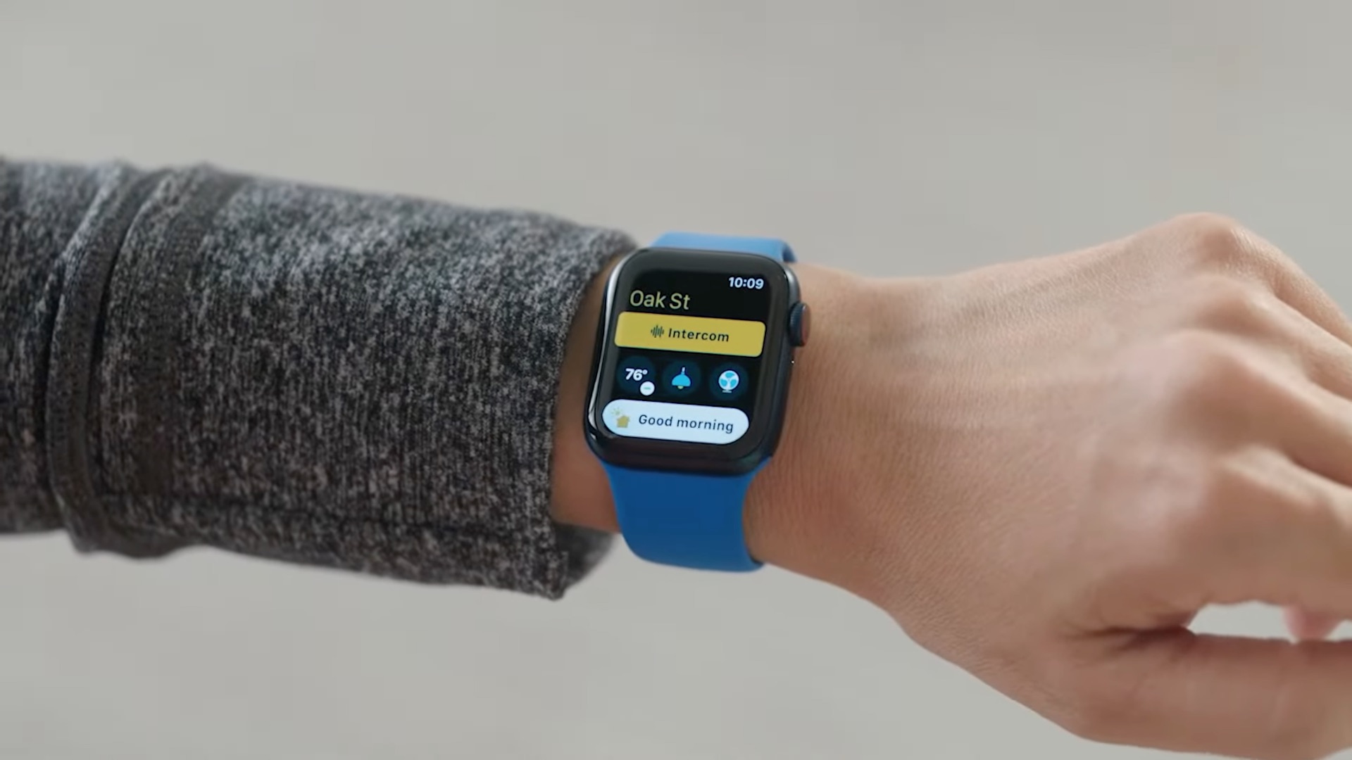 A photo showing a wrist wearing an Apple Watch running watchOS 8, with the Intercom button shown in the redesigned Home app