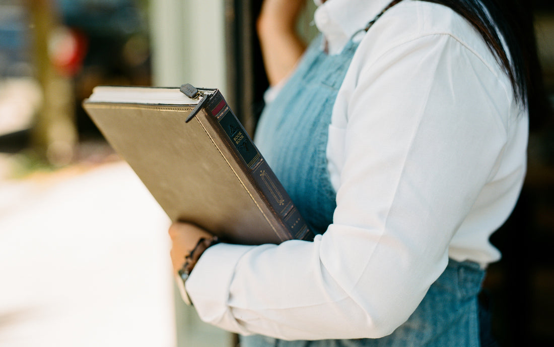 A woman is holding a closed BookBook case from Twelve South, designed for Apple's M1 MacBook Pro