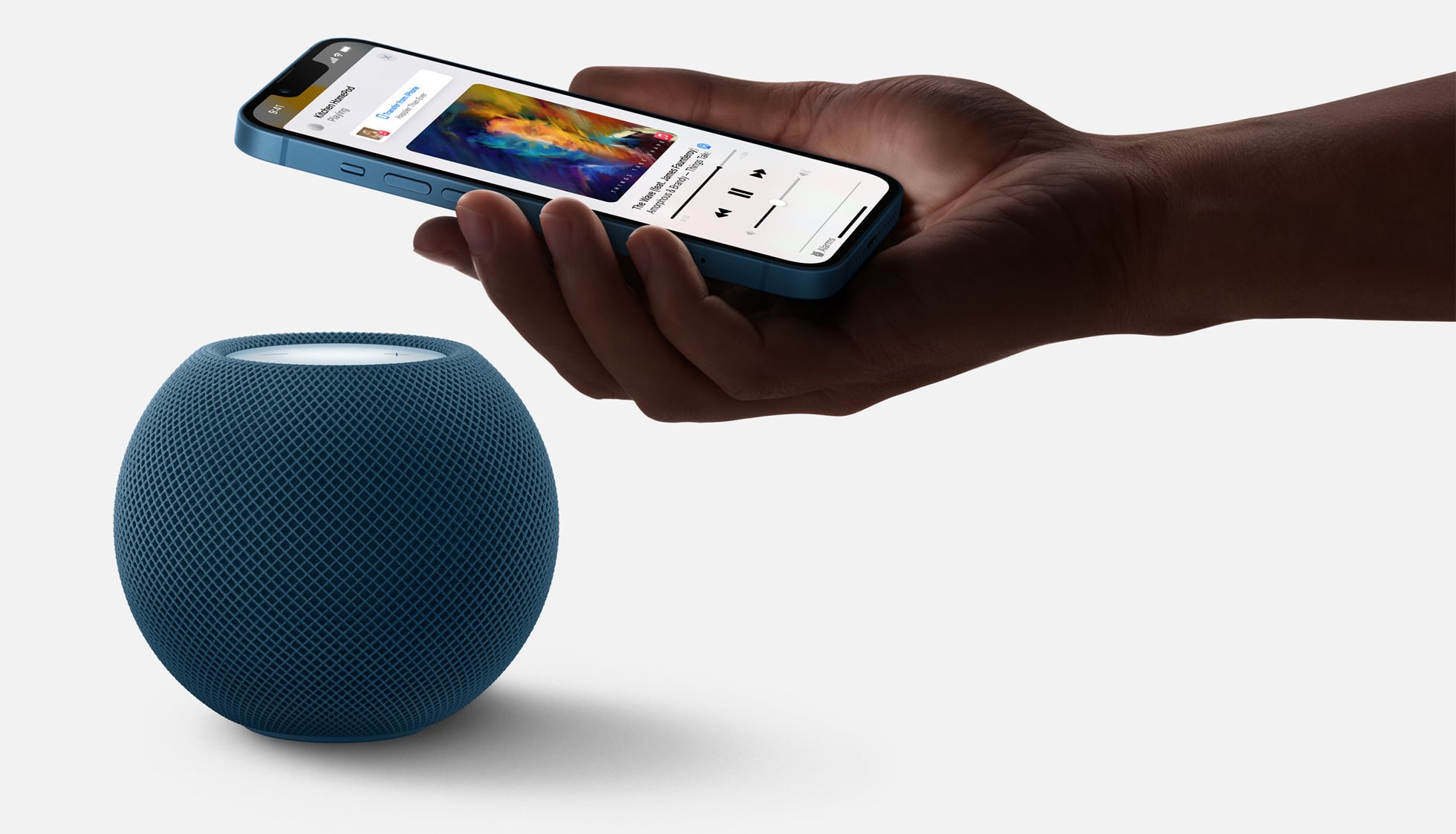 Apple's marketing image showing a male hand holding an iPhone near to a blue HomePod mini to transfer music