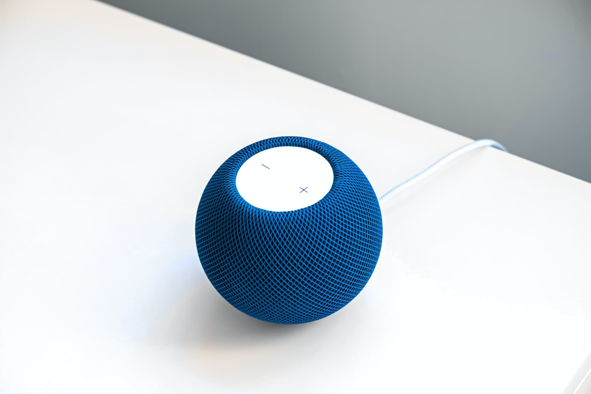 Blue HomePod mini on a white table