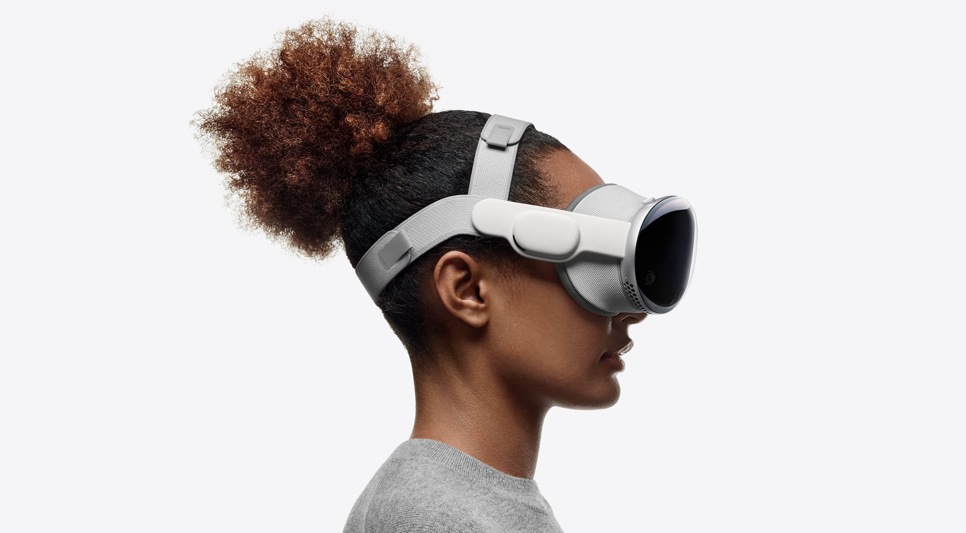 Woman wearing Apple's Vision Pro headset with Dual Loop Band, set against a sold gray background