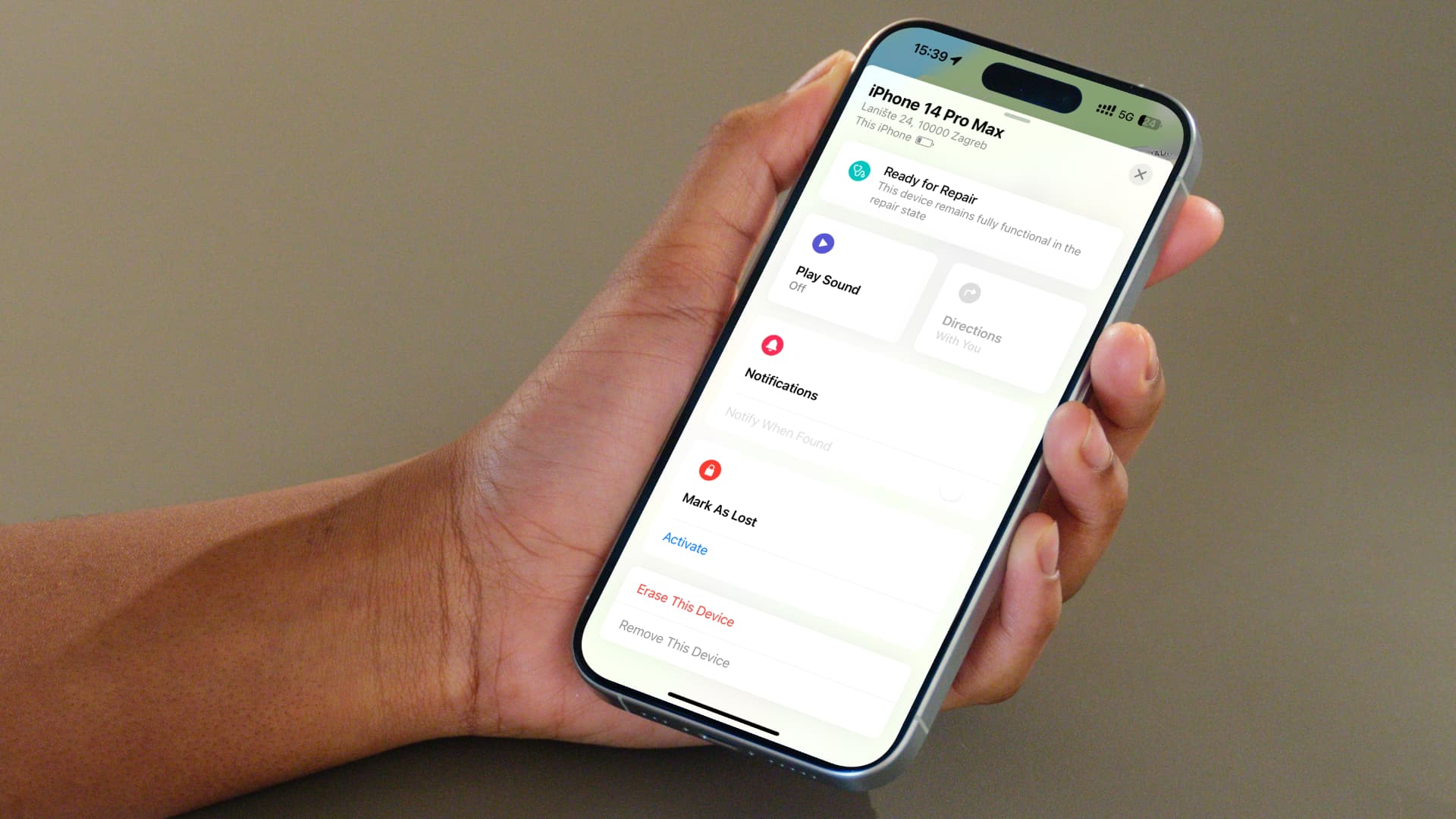Woman holding an iPhone running the Find My app displaying a repair state label