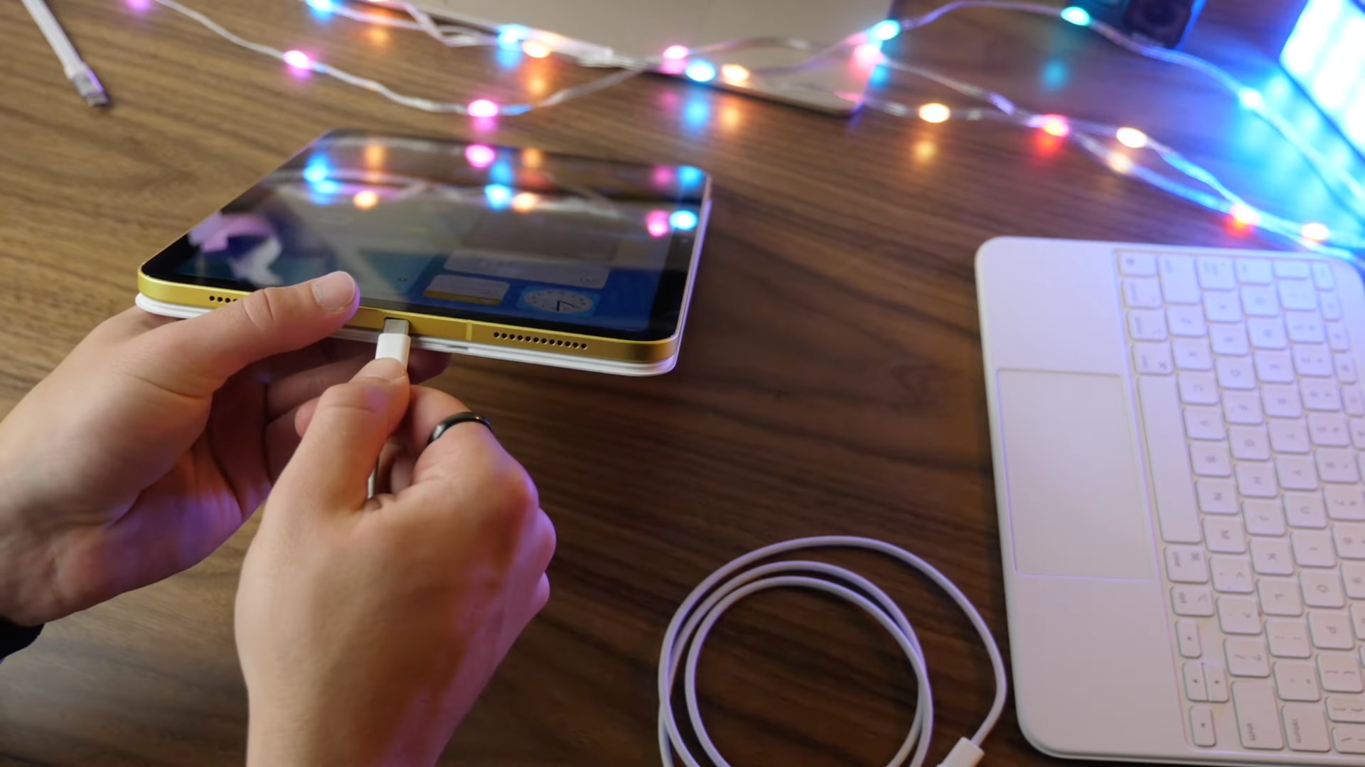 Young male's hands plugging a cable into the USB-C port of the tenth-generation iPad