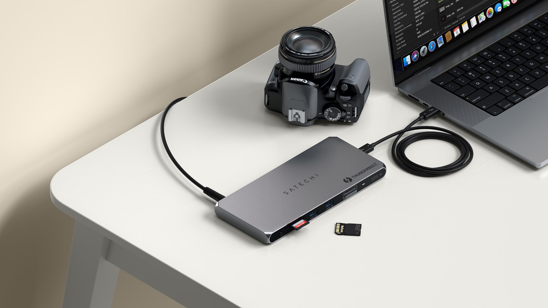 The rear ports on Satechi's Multi-Displays Thunderbolt Docking Station on a work desk next to a DSLR and a MacBook Pro laptop