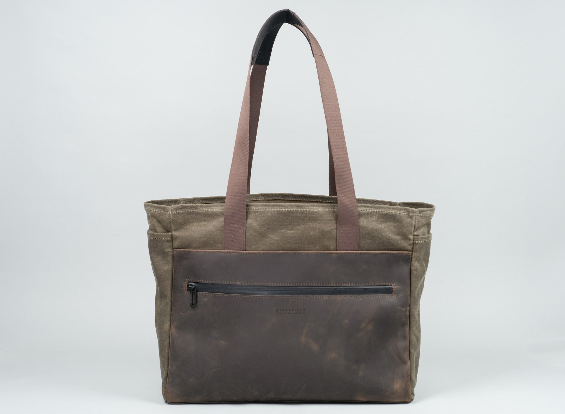 WaterField's leather cycling tote, closed and standing upright with the top handles raised vertically