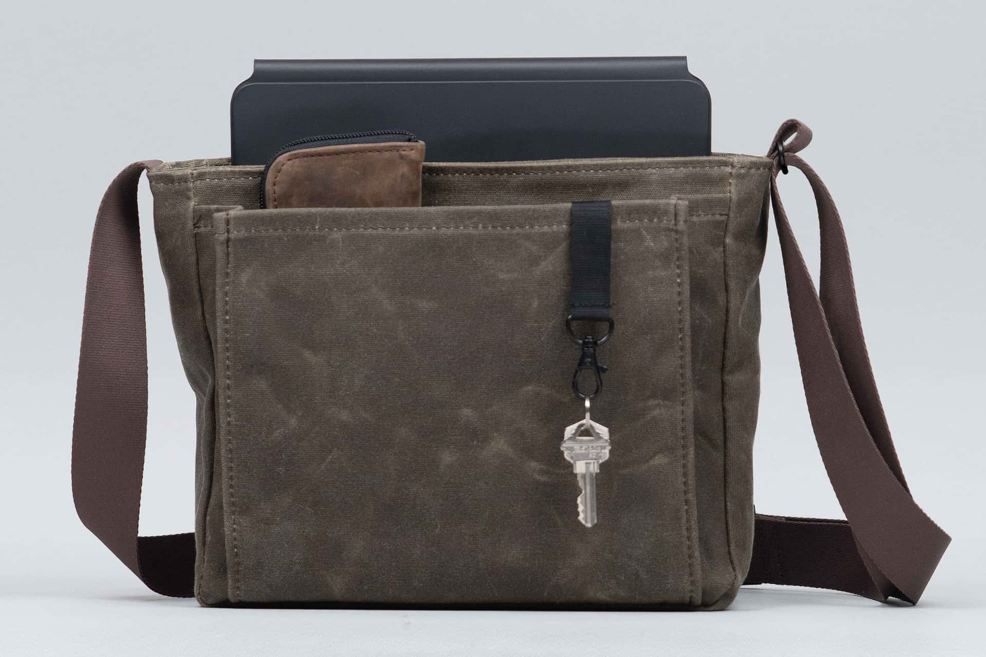 WaterField's Shinjuku messenger bag with an iPad half-inside and an iPhone with a key in the external pocket