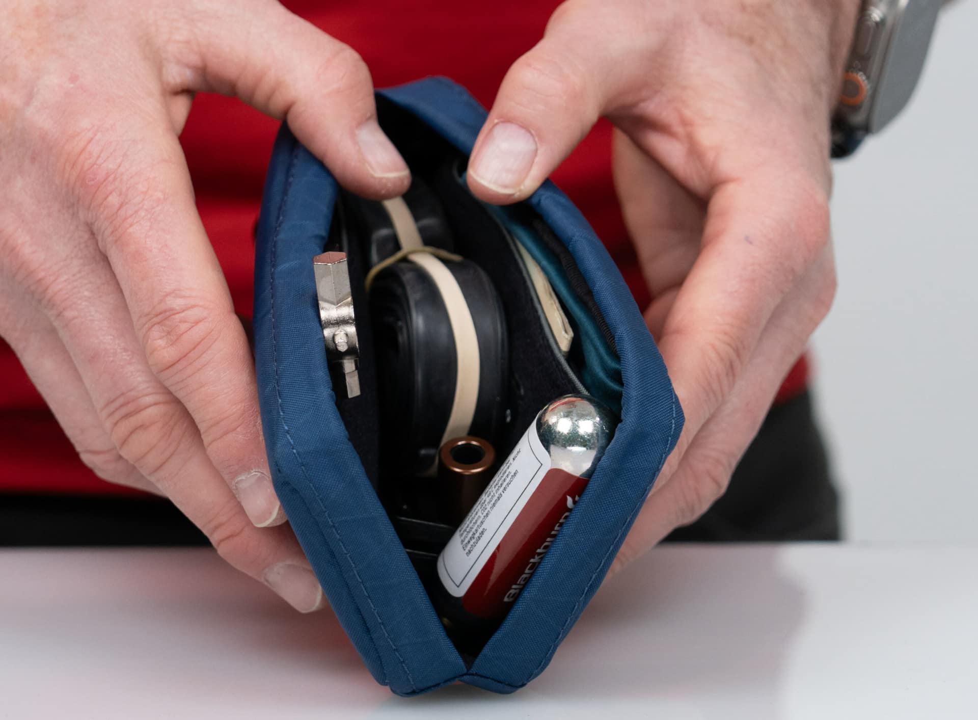 Male hand showcasing WaterField's cycling case full of items