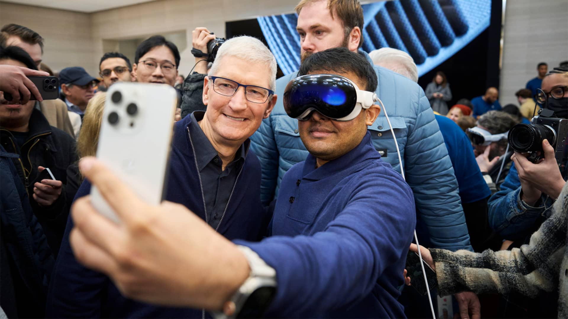 Apple CEO Tim Cook poses for a selfie with a customer wearing Vision Pro headset at an Apple retail store