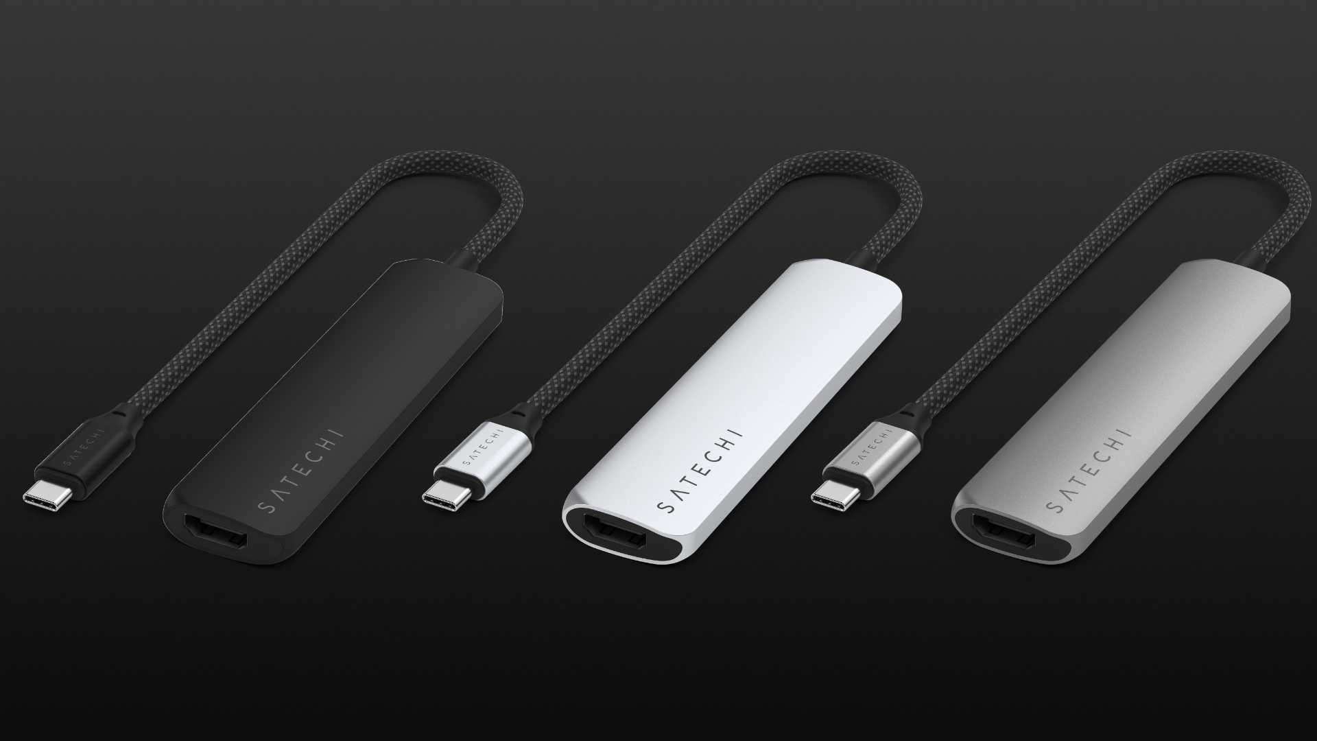 Three Satechi USB-C hubs in black, silver and space gray, set against a dark gradient background.