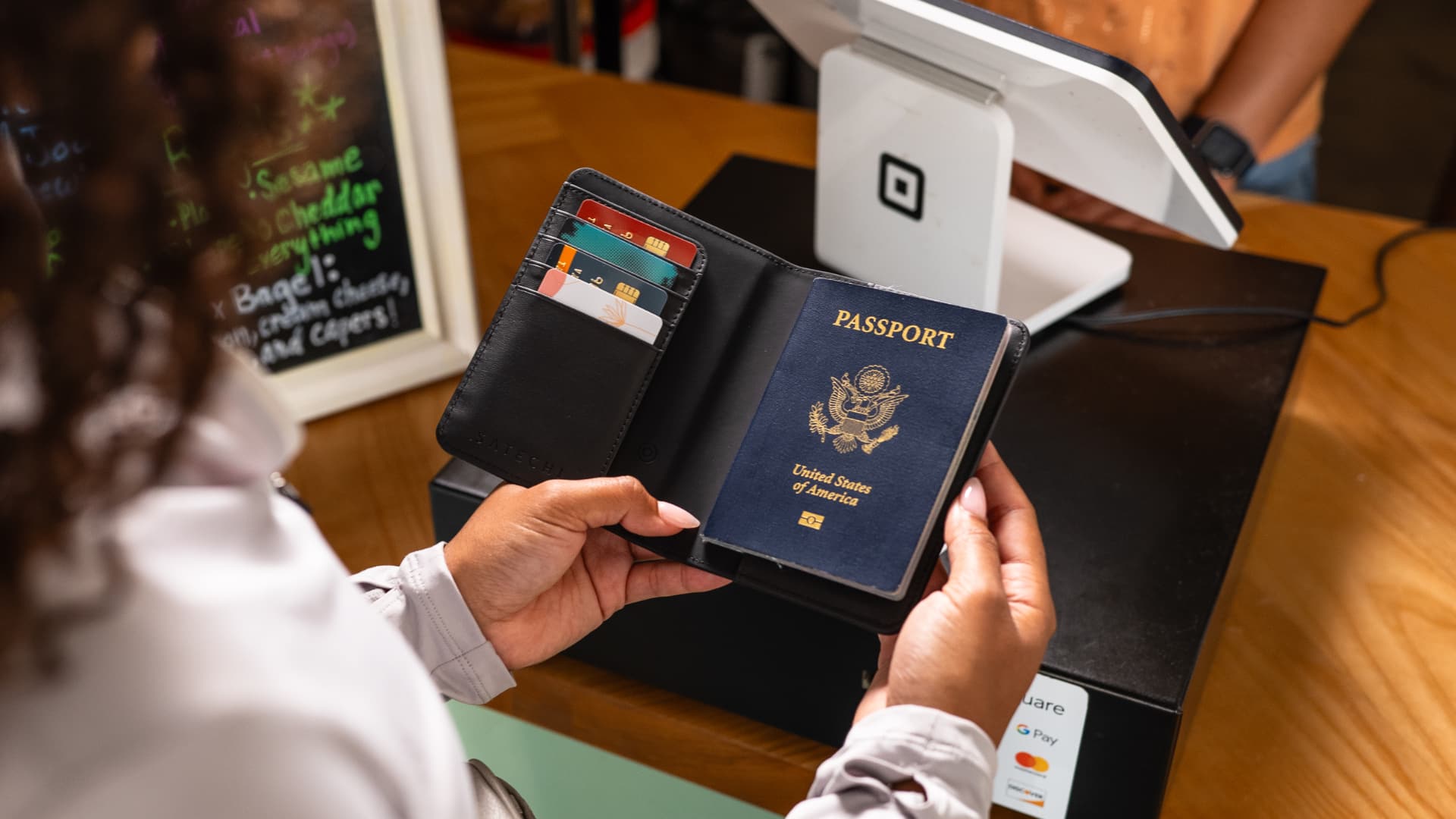 A woman's hands holding a wallet with a passport, airplane ticket and four cards