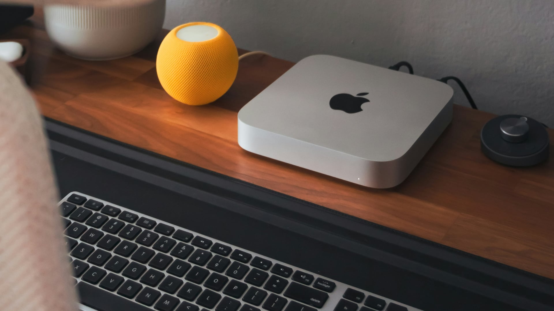 A mac mimi and a HomePod mini on a wooden desk.