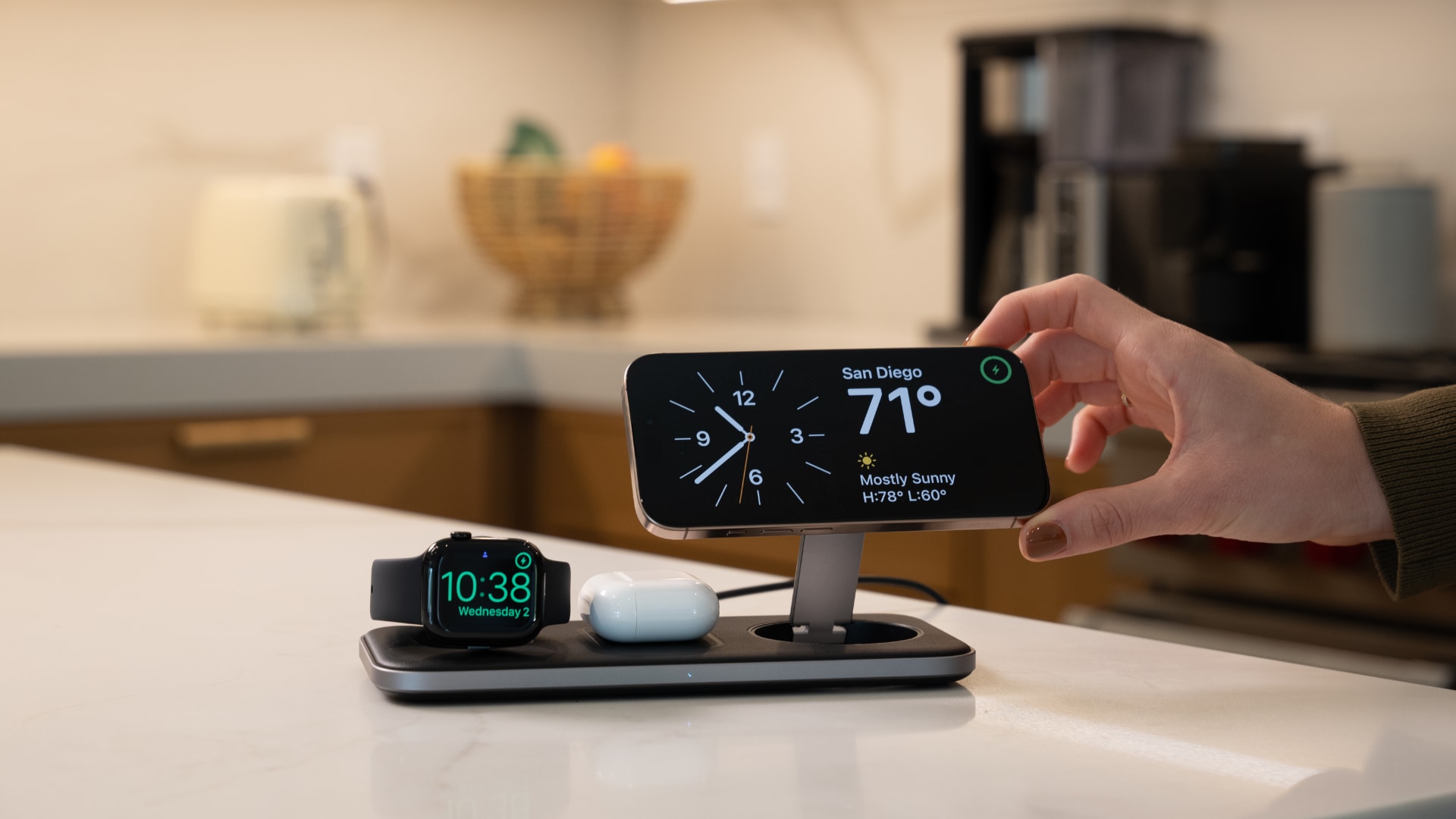 Satechi's Qi2 wireless charger on a kitchen desk, with Apple Watch, AirPods and iPhone in portrait orientation on it.