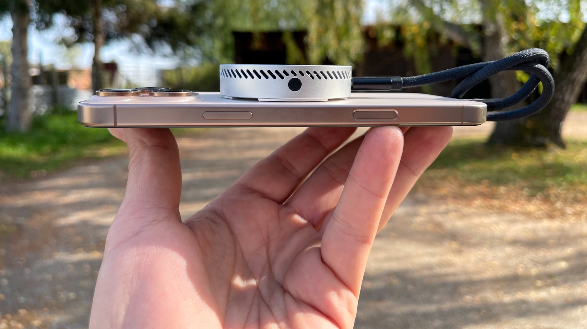 Dockcase MagSafe SSD enclosure on an iPhone's back, resting on male fingertips.