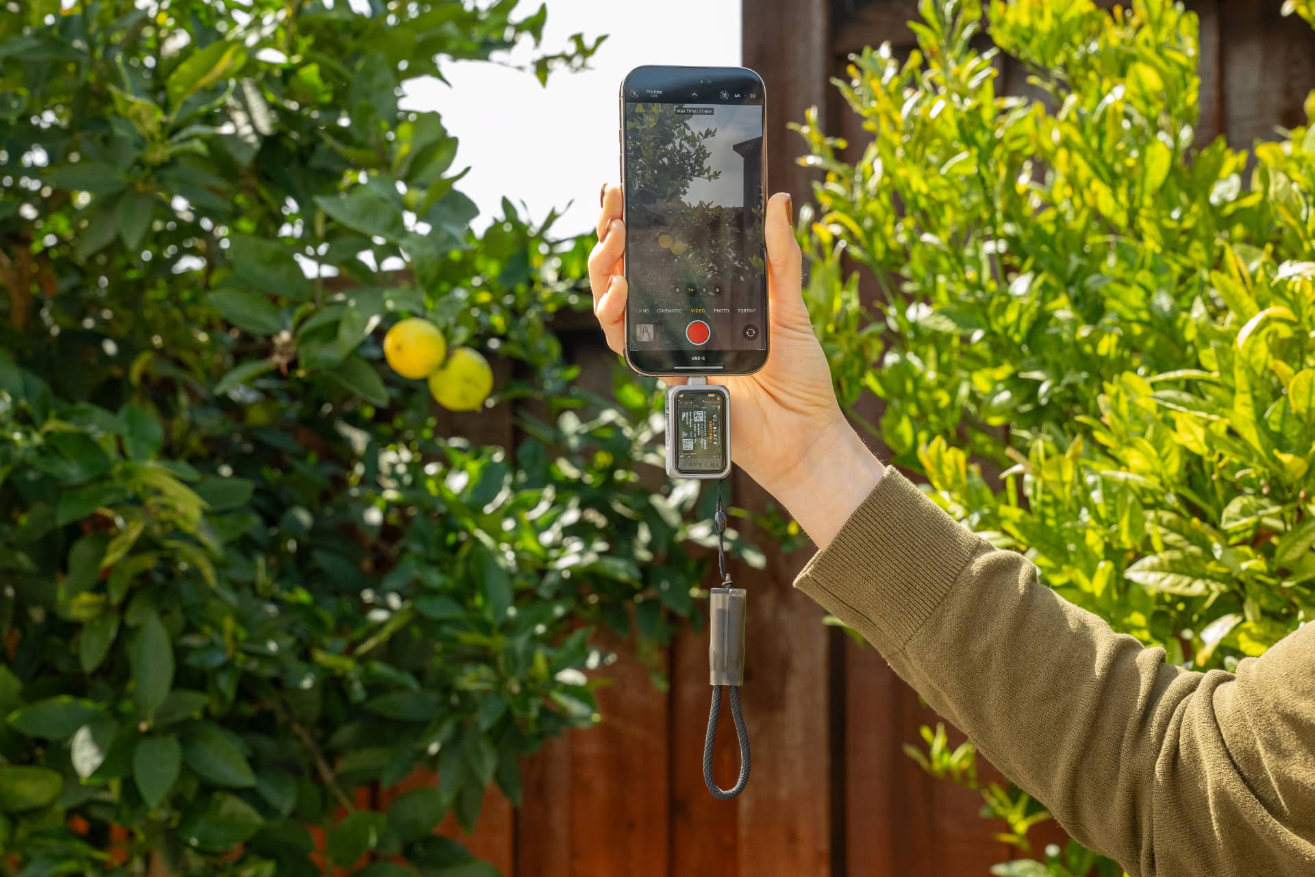 Hand holding an iPhone and shooting ProRes video, with a Satechi SSD enclosure plugged into its USB-C port.