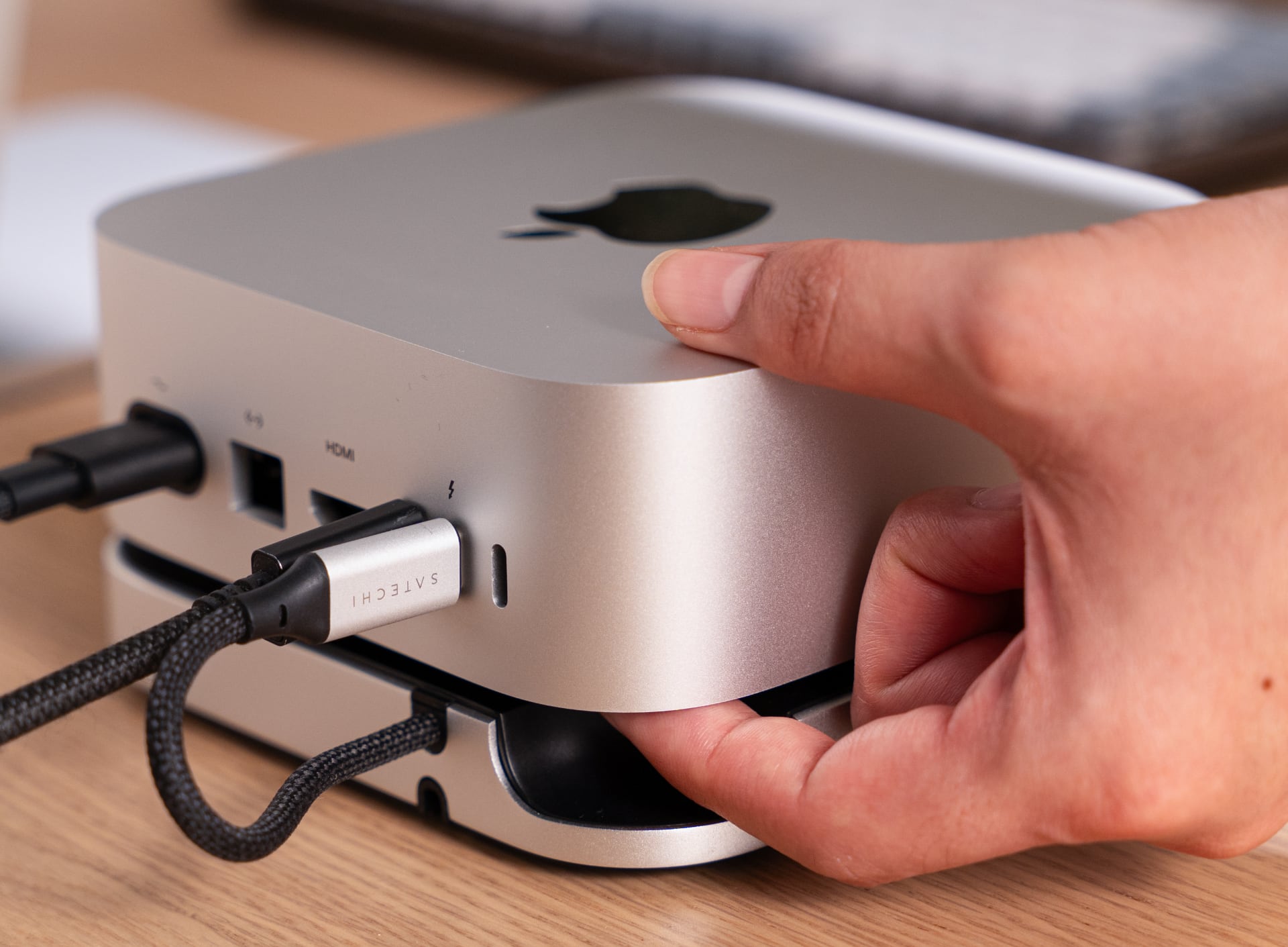 Mac mini sitting on Satechi's hub, with a hand reaching for the power button.