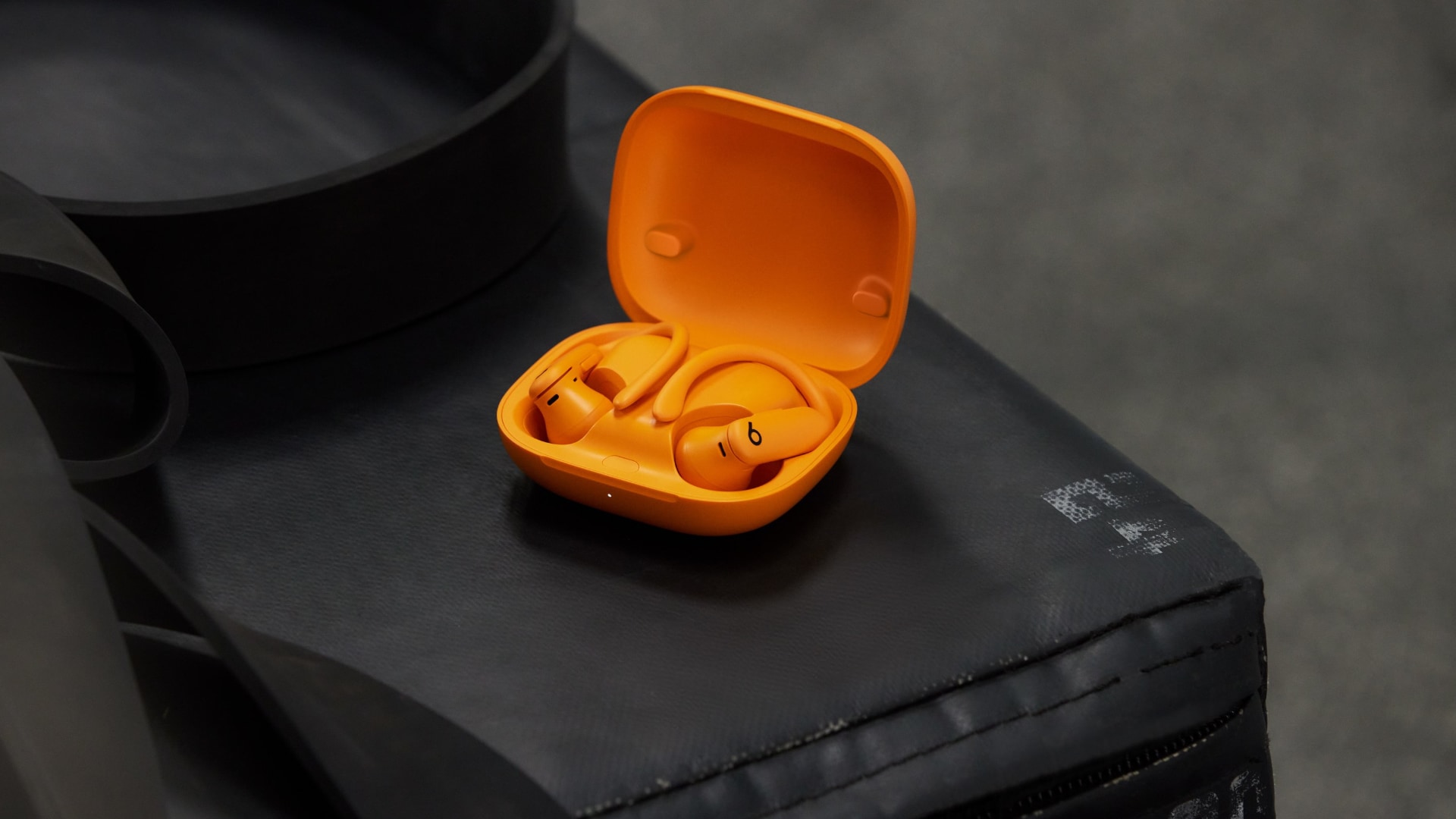 Powerbeats Pro 2 in the Electric Orange color resting in their charing case.