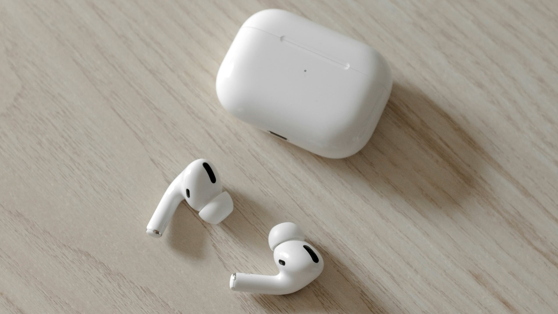 Apple's AirPods Pro earbuds on a wooden desk