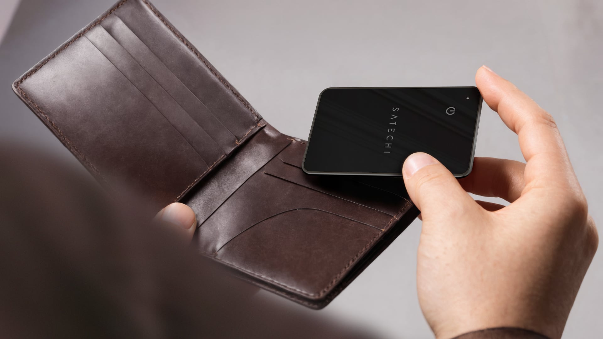 Hand inserting Satechi's credit card-sized card into a wallet.